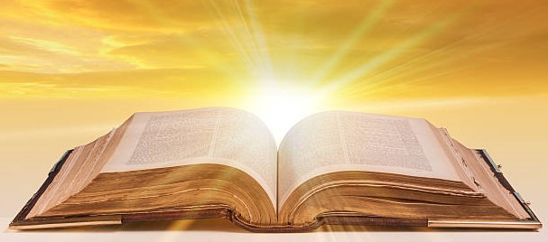 old antique bible as an open book with sunlight bursting from the pages
